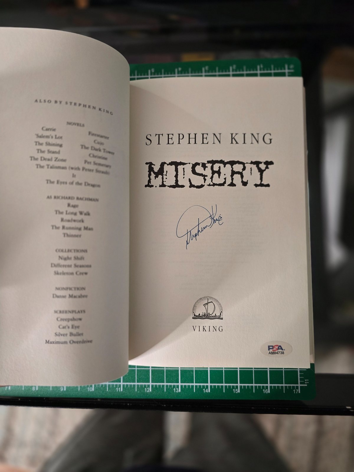 Open copy of Misery showing the title page, Stephen King signature, Viking publisher mark, and PSA certification sticker.
